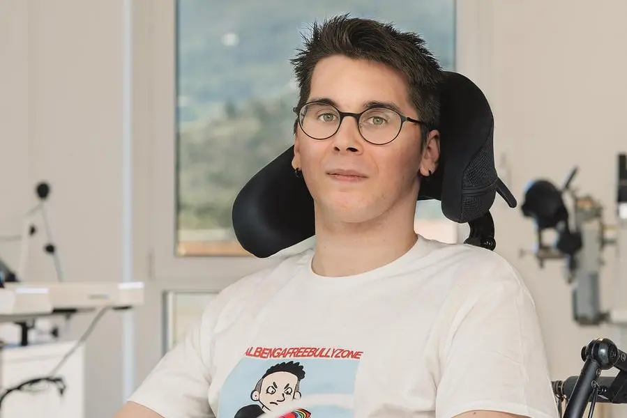 Il giovane Paolo Sarullo, 25 anni, originario di Albenga, \\u00E8 diventato suo malgrado il volto di una ferita collettiva. Il 19 maggio 2024, un tentativo di rapina finito male gli ha cambiato la vita: un pugno in faccia, la caduta, il trauma cranico gravissimo. Dopo tre mesi di coma e tre interventi delicati, il suo percorso riabilitativo presso la Fondazione Don Gnocchi di La Spezia lo ha riportato alla parola, all\\u2019alimentazione autonoma, ai primi movimenti. La sua storia \\u00E8 approdata anche sul palco del Festival di Sanremo come appello contro la violenza giovanile. La foto \\u00E8 di Federico Schenone.