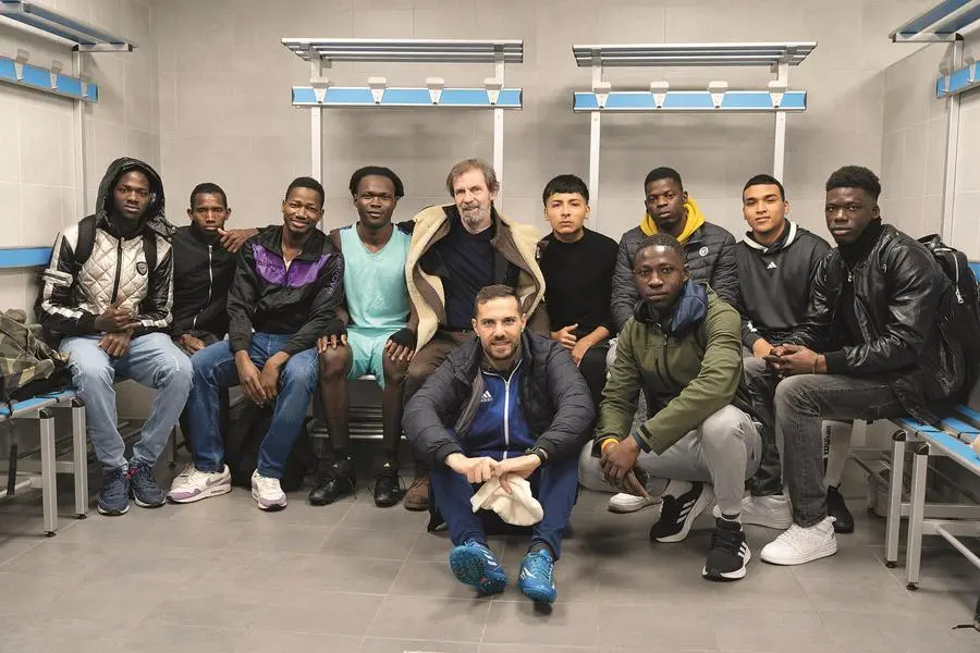 Alcuni giocatori della Real Refugees negli spogliatoi con (al centro) gli allenatori Filippo Galli e (seduto a terra) l'ex calciatore siriano Fadi Albitar