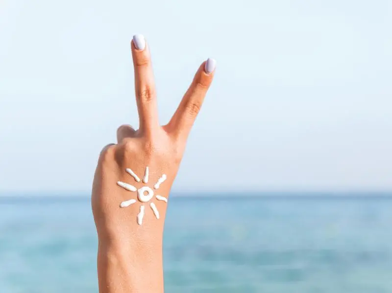 Crema solare su viso e collo: vale la regola delle due dita