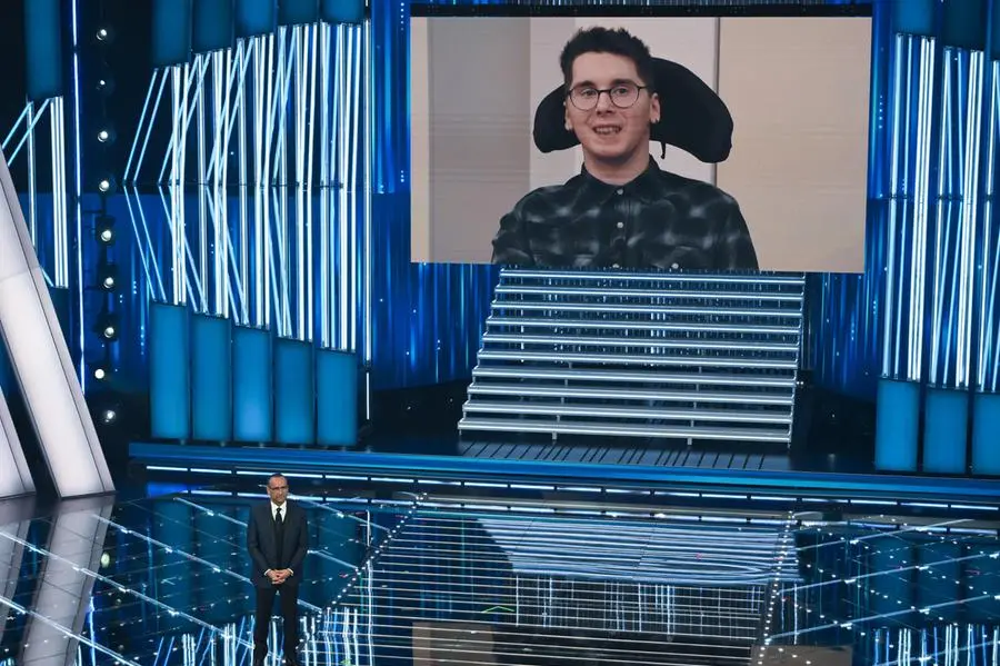 Il giovane Paolo Sarullo, vittima di un\\'aggressione, in collegamento con il Teatro Ariston durante il Festival di Sanremo 2026. ANSA/ETTORE FERRARI , ANSA